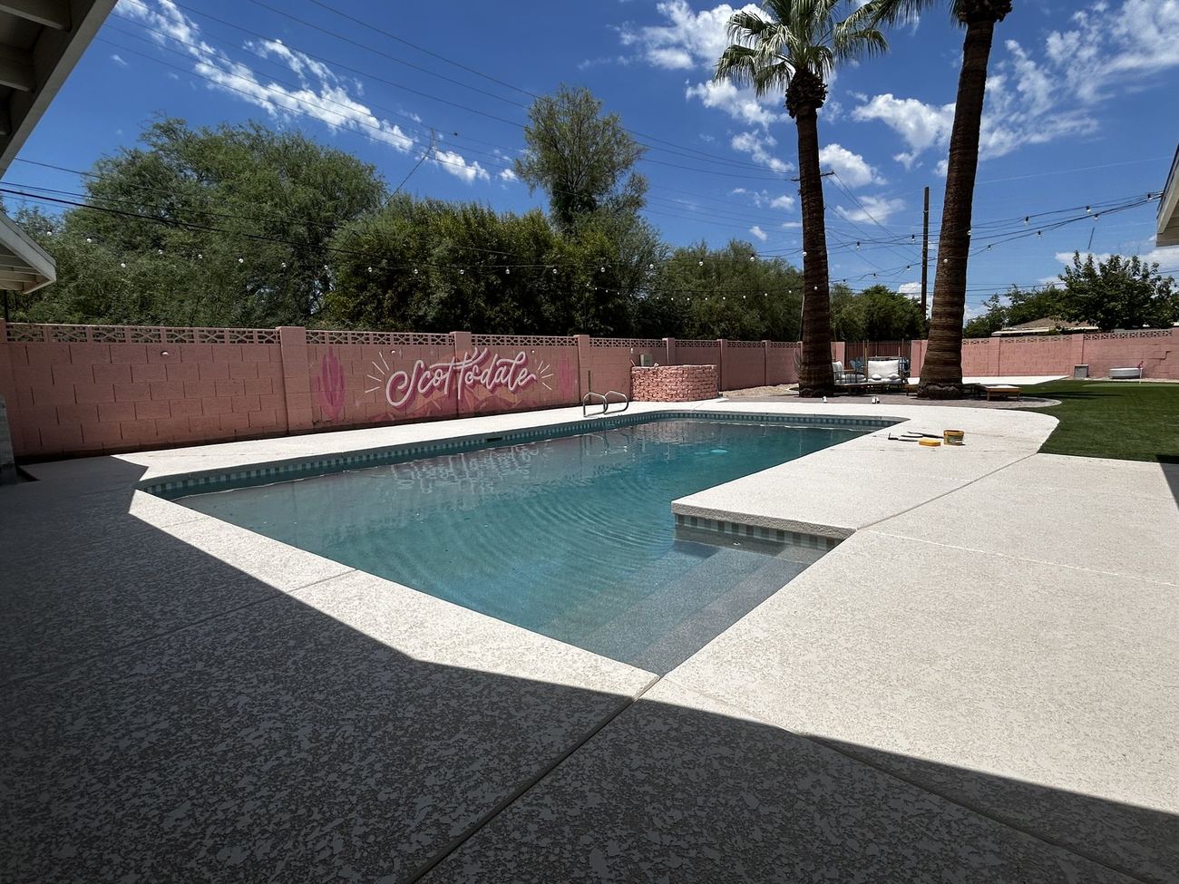 Finished pool at a Scottsdale Airbnb remodel, palm trees and pink perimeter wall