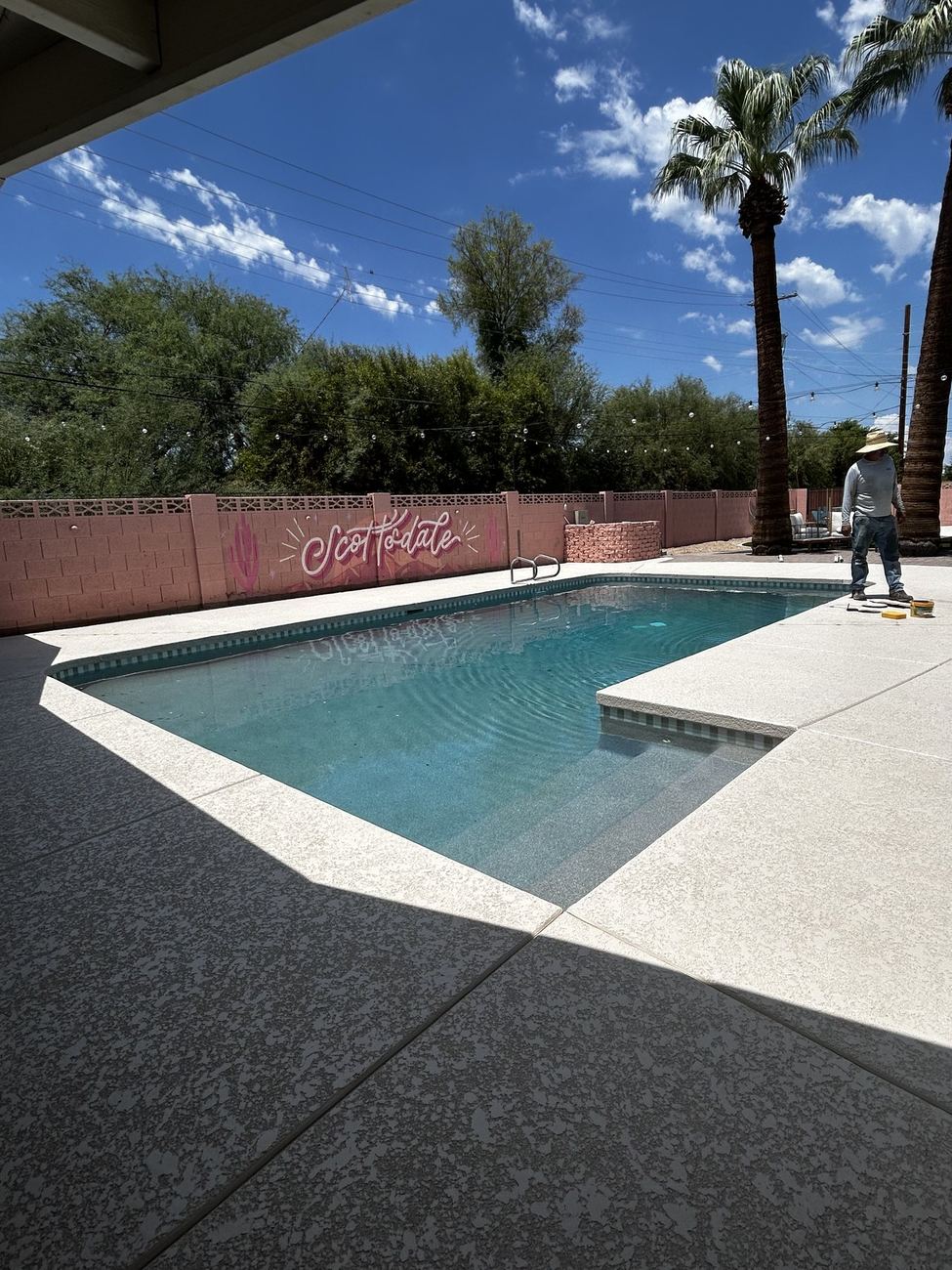 Crew member finishing touches poolside with turquoise water