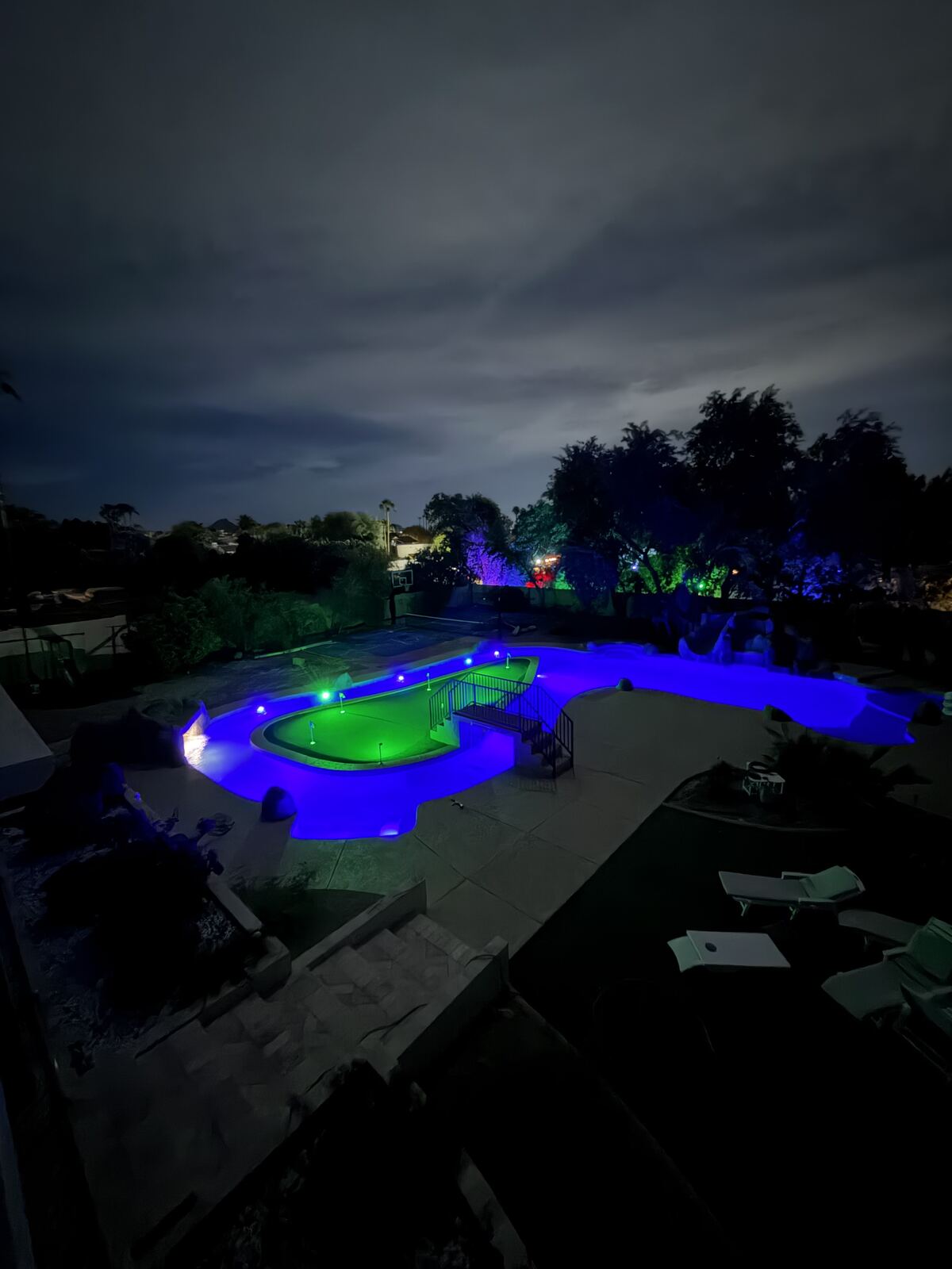 Aerial night view of a custom lazy river and putting-green island, lit up