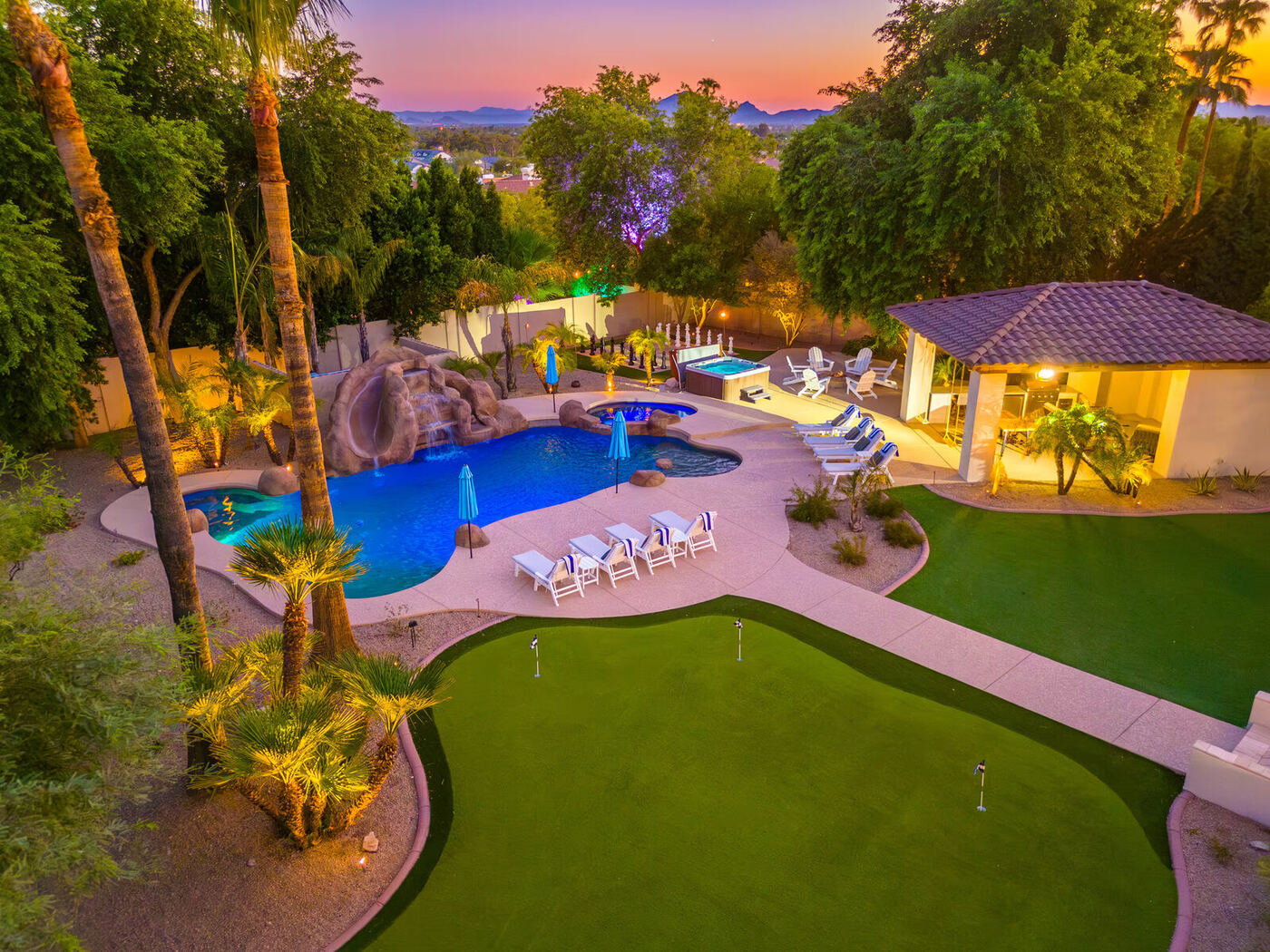 Before: the original pool, grotto with rockslide, spa, and ground-level putting green at dusk
