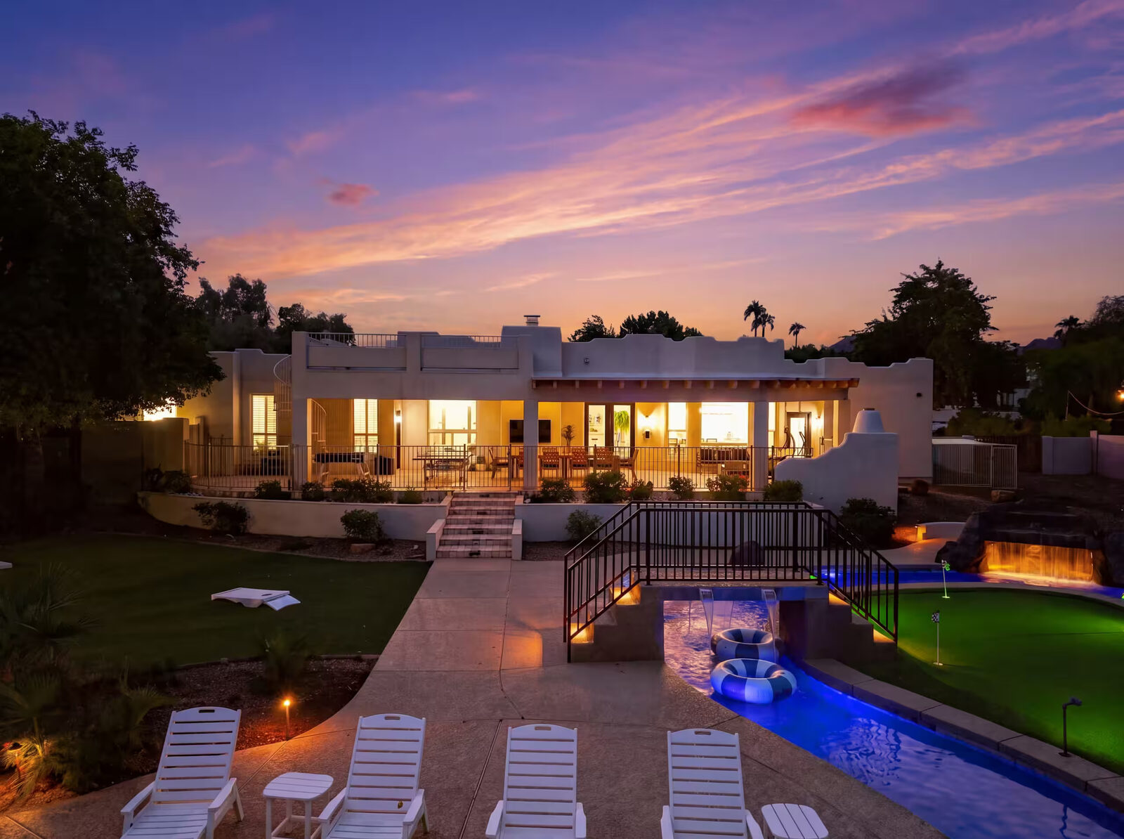 Photo of the house exterior and back patio at dusk, overlooking the backyard