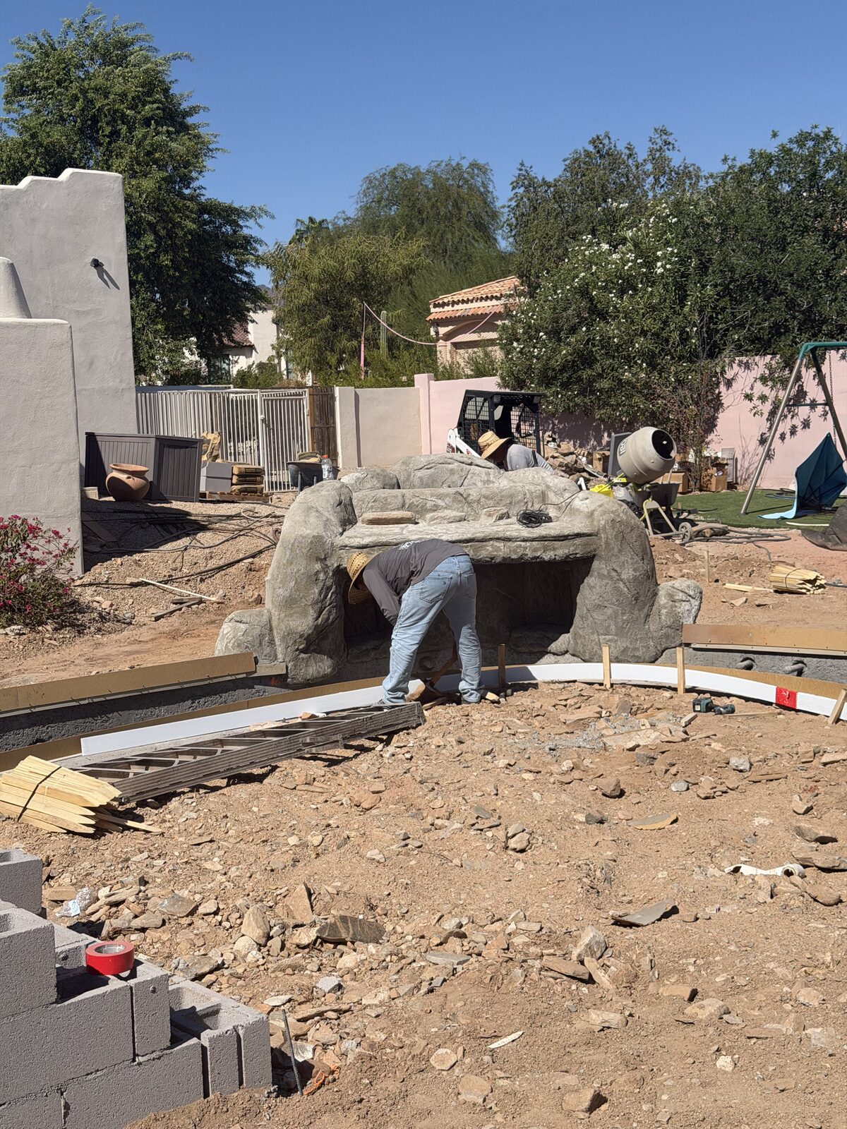 Crew member working inside a rockwork form, with cinder block courses and forming boards visible